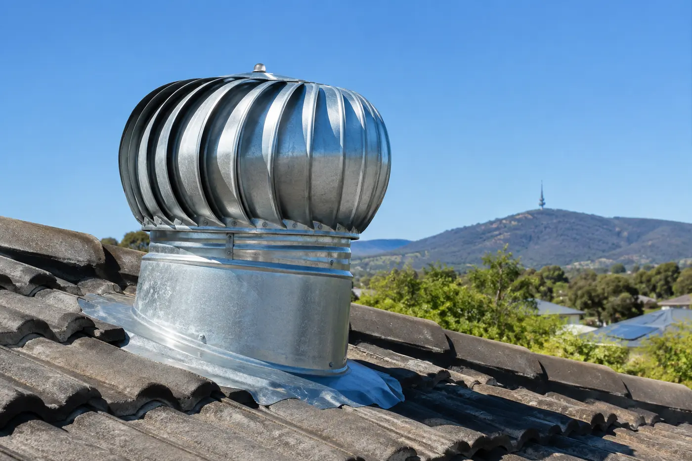 A whirlybird turbine vent on a tiled Canberra rooftop against a clear sky